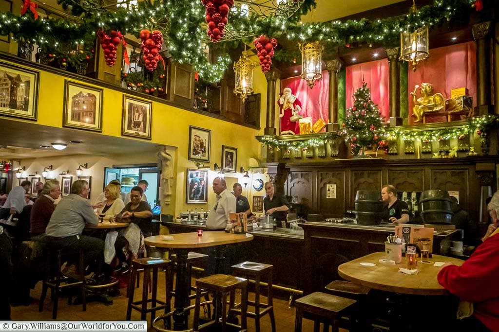 Inside the Christmas decorated Bierhaus en d'r Salzgass, a traditional Kolsch pub with beer barrels on the bar.