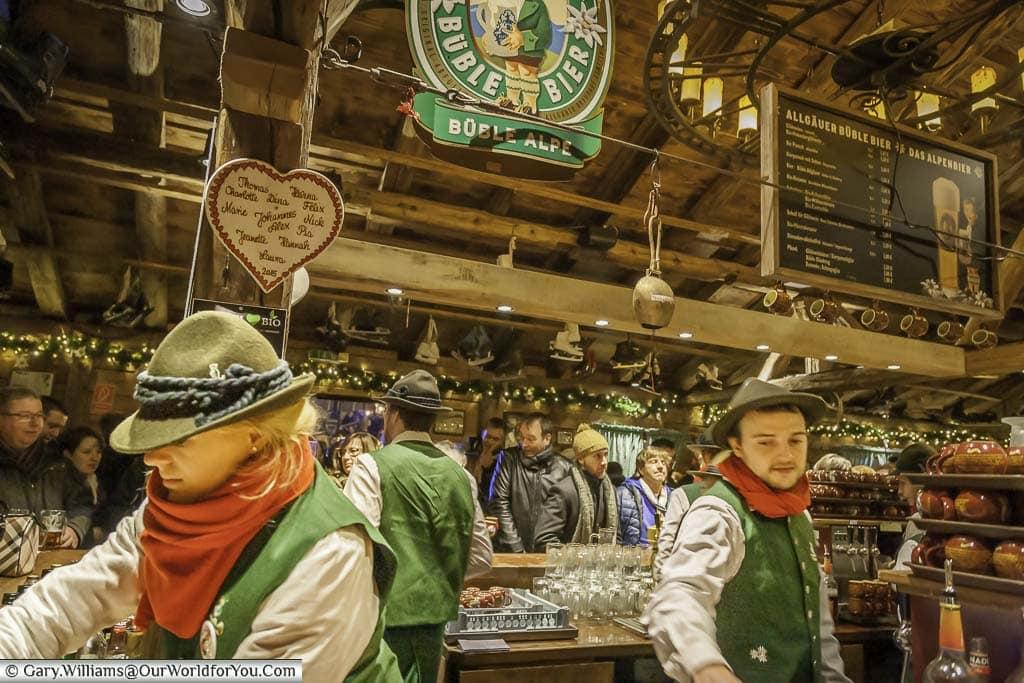 The staff behind the counter of the alpine ski lodge, dressed in traditional costumes in the Heinzels Winter fairytale christmas market in cologne, germany