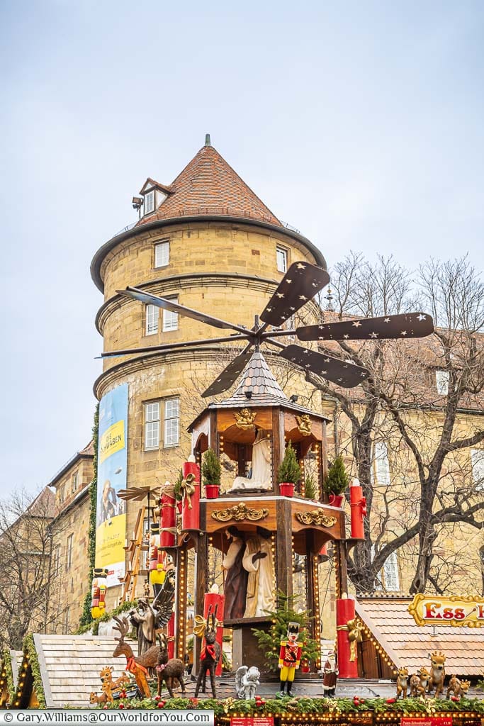 A german christmas advent wheel on top of a drinks stall, in front of a historic tower, in the heart of stuttgart, germany
