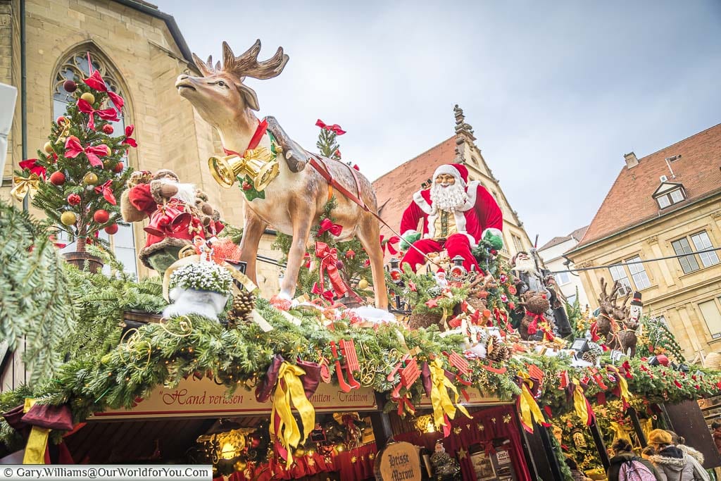 A christmas market stall in stuttgart decorated with red and gold ribbons and a single reindeer pulling Santa on his sleigh.