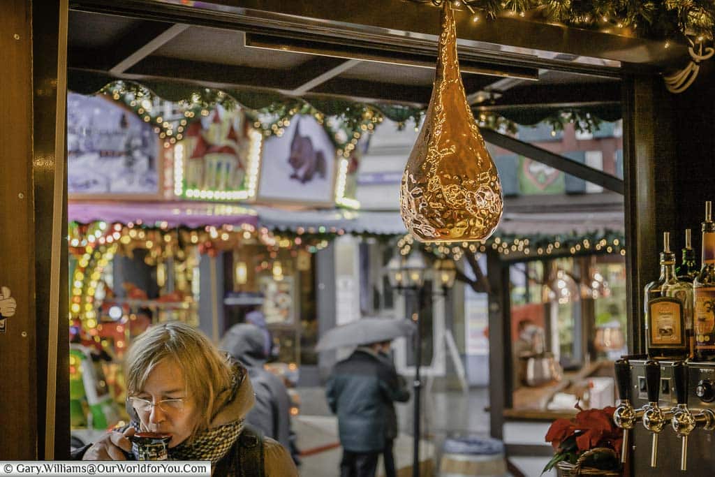 A lady sipping at a mug of glühwein at the Nicholas Village Christmas Market in Cologne