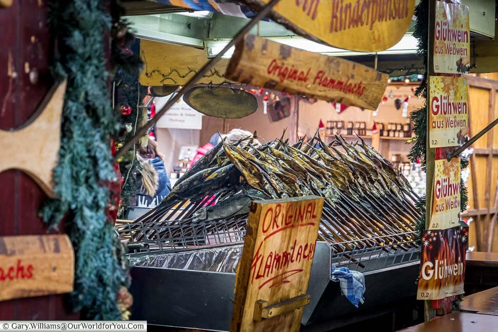 Racks of intertwined mackeral fish cooking on skewers over charcoal on a christmas market stall in stuttgart, germany