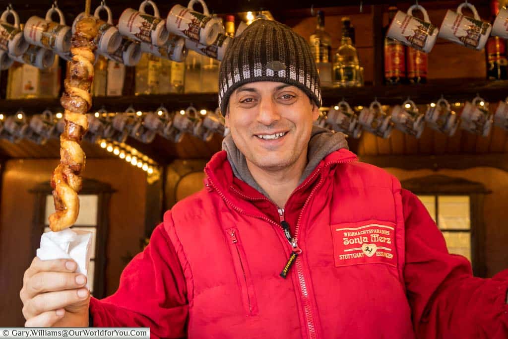A smiling vendor handing over his bread and meat kebab on the Stuttgart Christmas Markets