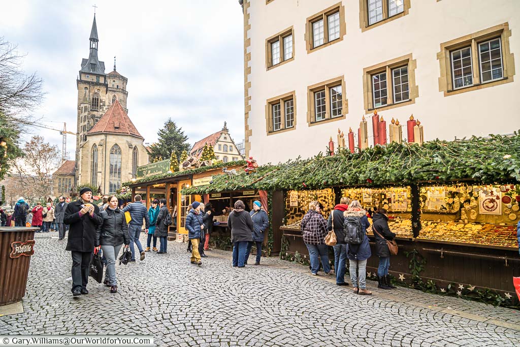 A cobbled pedestrian street lined with christmas market stalls and an impressive church in the background of Stuttgart at christmas