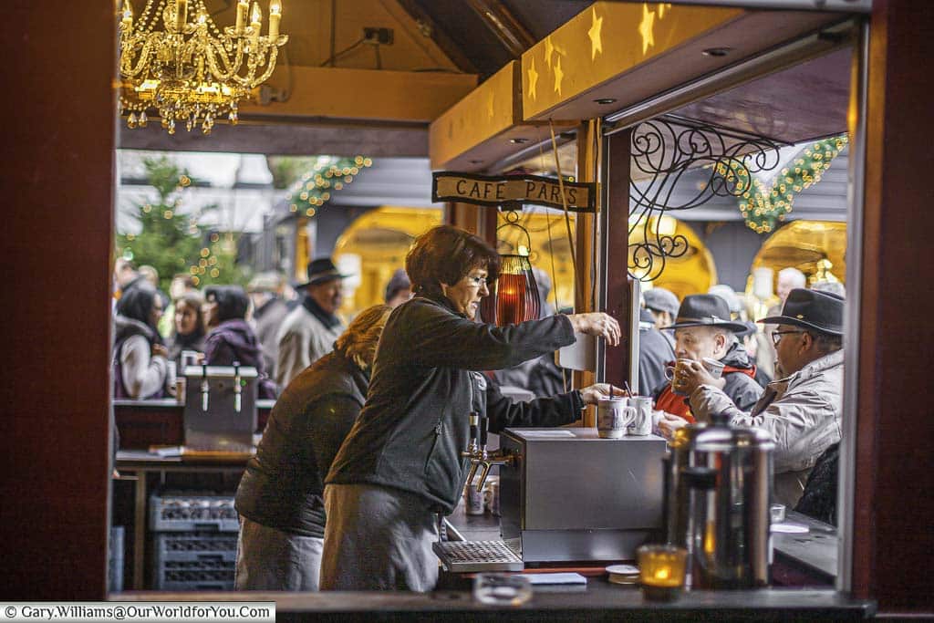 A looking inside the drink stall called 'Cafe Paris' in the centre of the Christmas Angel Market in Cologne with the staff handing our mugs of gluhwein