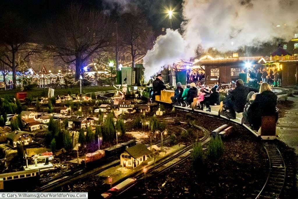 Stuttgart's miniature railway full of small children with their parents in the early evening after the sun has gone down.