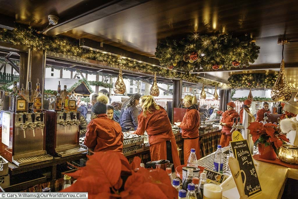 Looking out at the staff working in a busy, well decorated, glühwein cabin on the Nicholas Village Christmas Market in Cologne