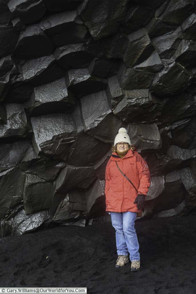 Janis standing next to the hexagonal structure of the Basalt rock formation on Reynisfjara Beach