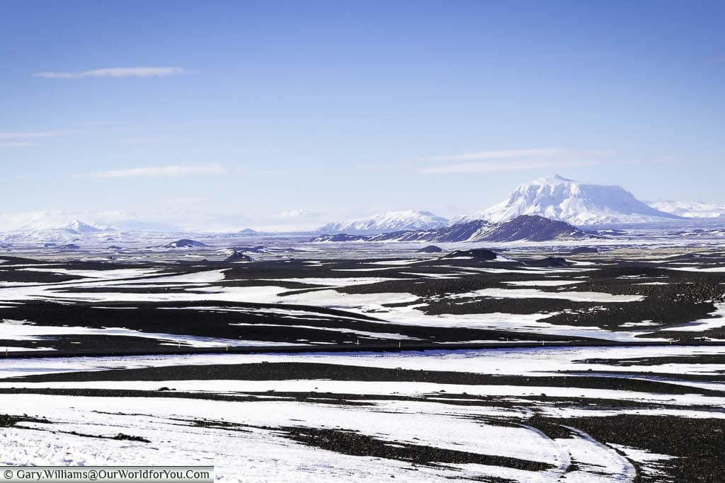 The wilderness of eastern Iceland with snow-capped peaks dotted between a patchwork of snow-covered dark volcanic soil