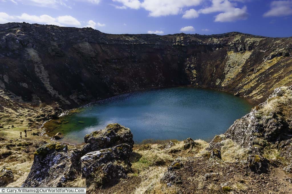 Looking down from the rim of the Kerið volcanic crater to the crystal blue lake formed within it.