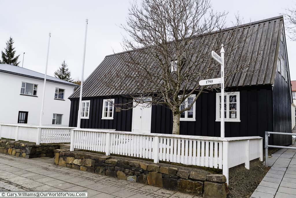 A black wooden home with a white picket fence that is Akureyri's oldest house from 1795