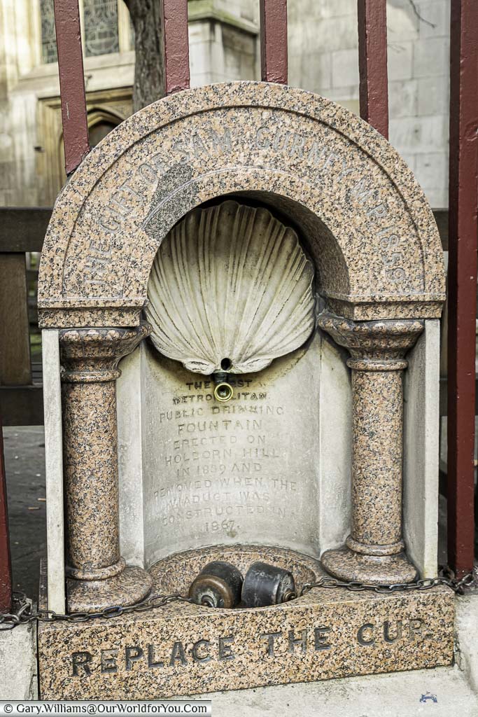 A pink marble water fountain from 1859 set on the edge of the street