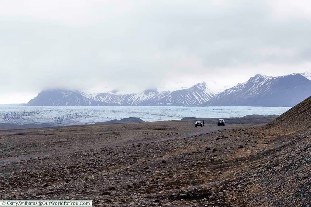 The pale blue ice layer of the Skaftafellsjökull glacier against a backdrop of snow-covered mountains