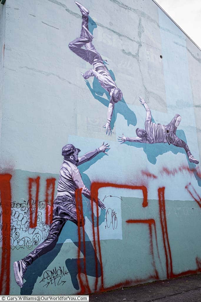 A mural of three guys possibly breakdancing on the side of a building in Reykjavik, Iceland.
