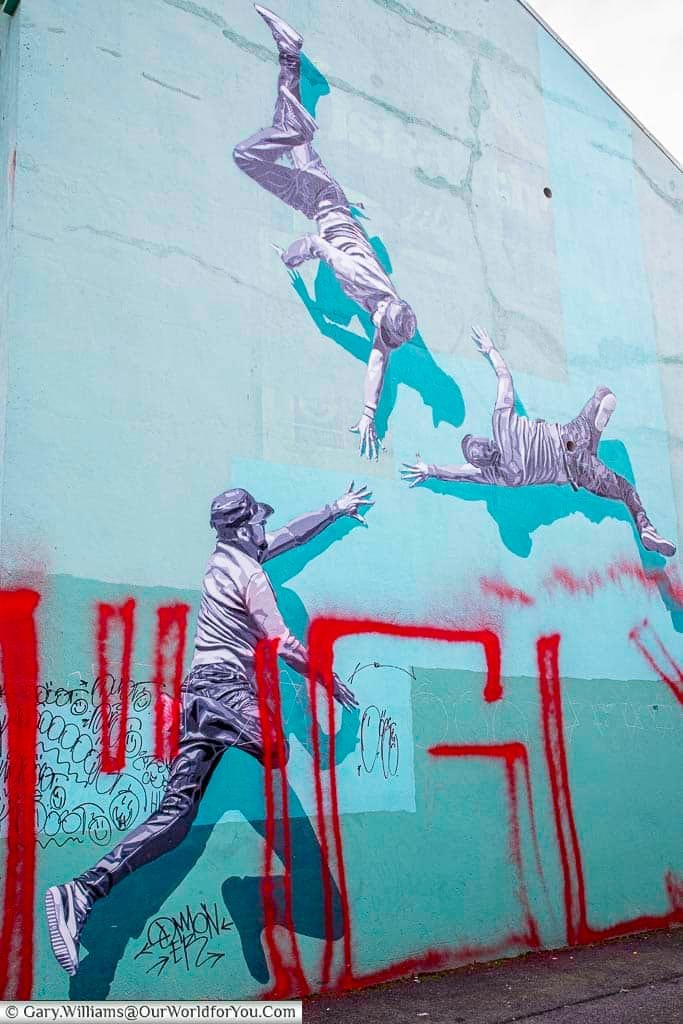 A mural of three guys possibly breakdancing on the side of a  building in  Reykjavik, Iceland.