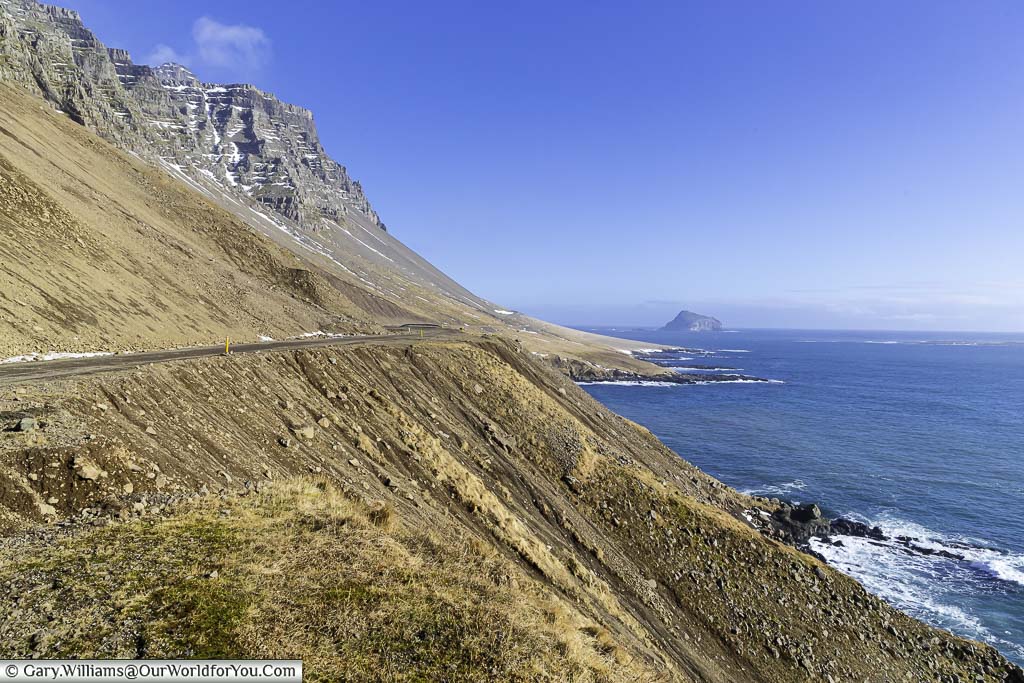 A view of the gravel route 955 and the blue ocean lapping against Eastern Iceland