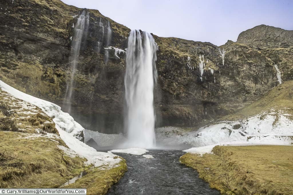 The Seljalandsfoss waterfall, as seen from the bridge that crosses the river it feeds.