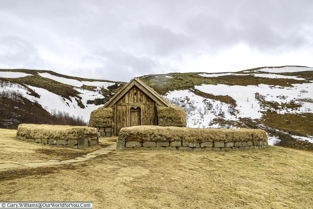A small Icelandic wooden hut surrounded by a stone wall, all covered with turf as insulation.