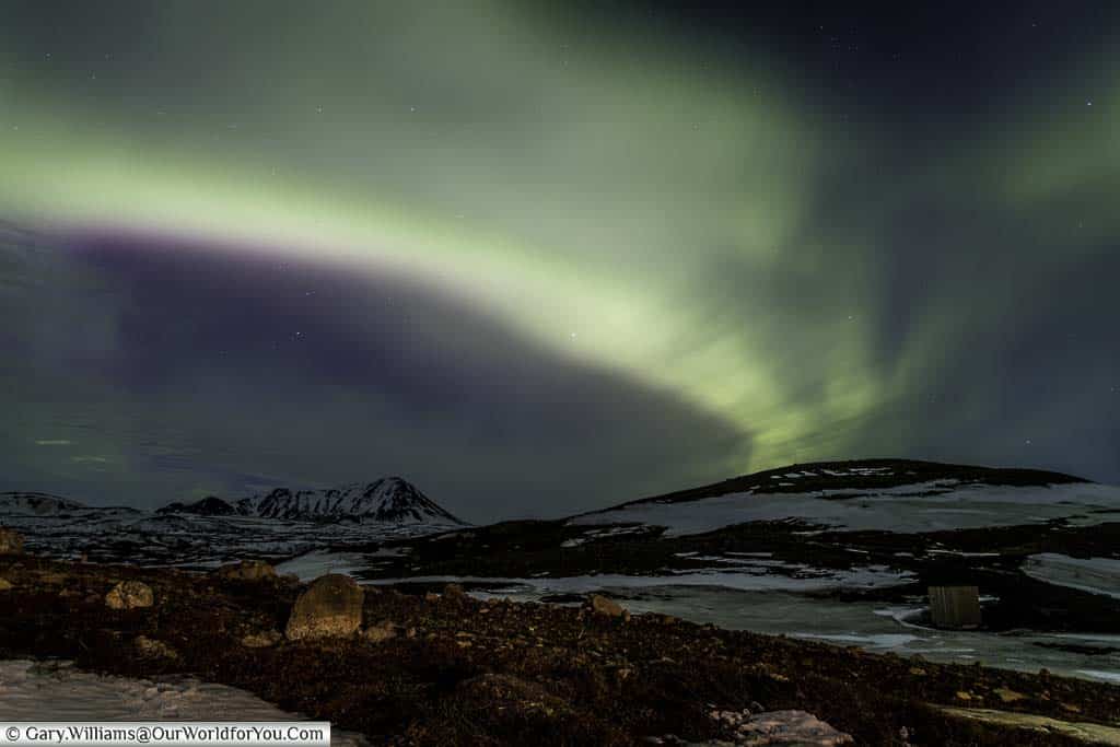 A band of green lights of the Northern Lights over the mountains just outside Reykjahlíð in Eastern Iceland