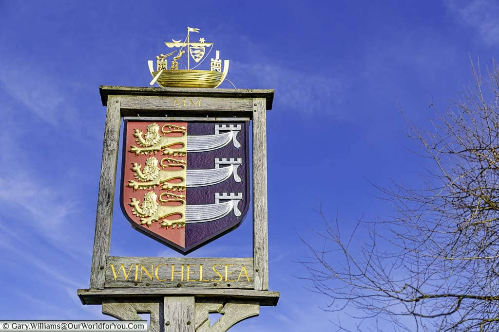 The Winchelsea village sign featuring the coat of arms of the Cinque Ports with a golden galleon on top.