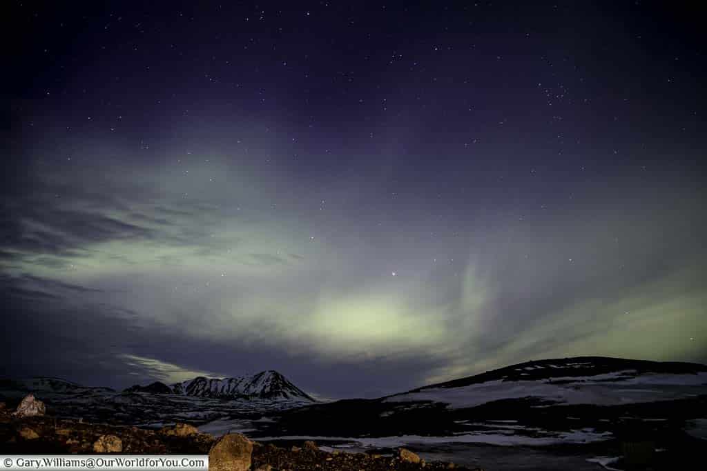 The sky at Reykjahlíð is filled with the blue/green hues of the Northern Lights.