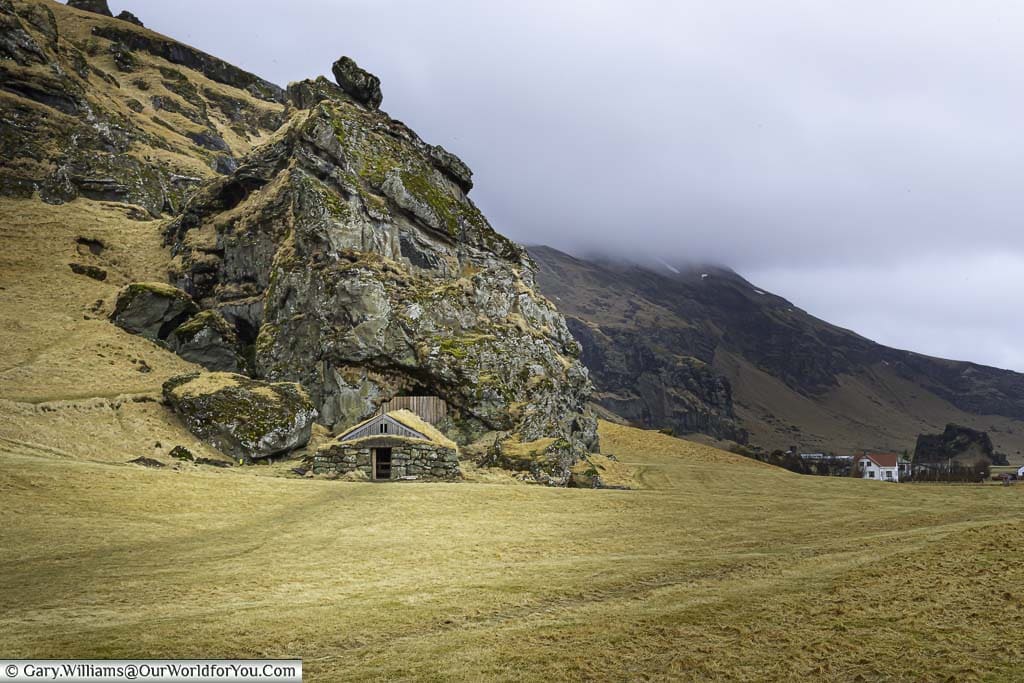 A small wooden hut in front of a rocky outcrop by the side of Iceland's route one