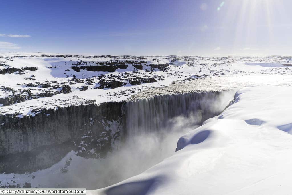 The v-shaped crevice in a snow-covered landscape as the Dettifoss waterfall in Iceland drops to the river below.