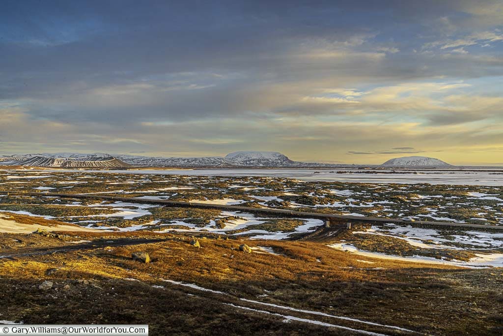 The sun setting over the frozenlake mývatn in eastern iceland surrounded by mountains and extinct volcanoes