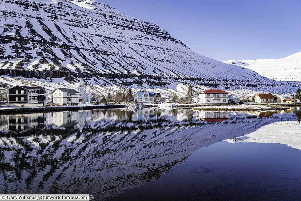 A mirror reflection of lakeside homes against a backdrop of mountains in Seydisfjordur, Iceland