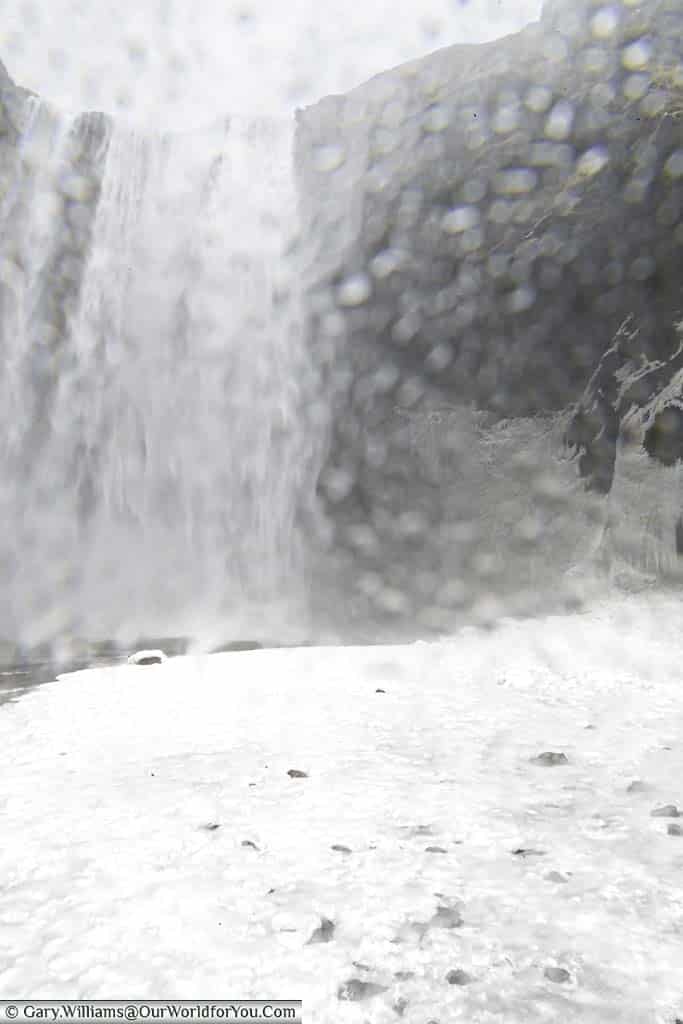 A shot of the Skógafoss waterfall in iceland from close range where the lens is covered in water droplets from the spray