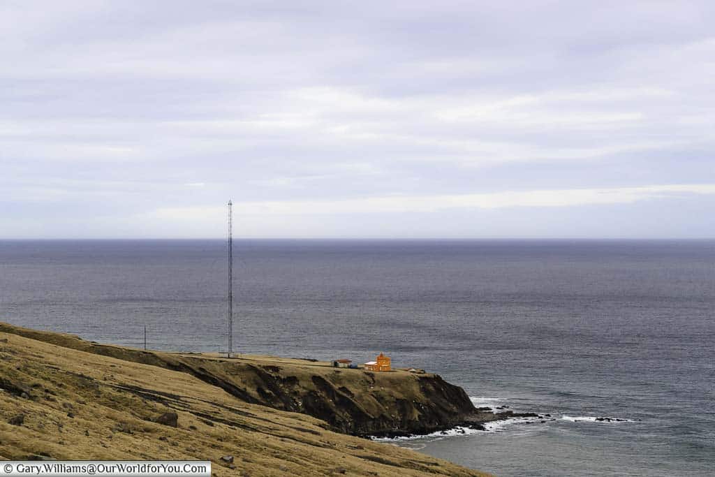 The orange Trollaskagi Lighthouse on a bleak outcrop of rock in Northern Iceland