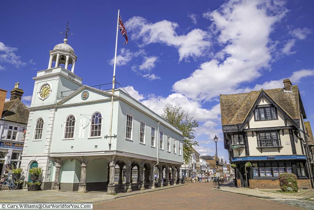 The pale green historic Faversham Guildhall stands proudly in the centre of the Market Square displaying a Union Flag fluttering on a bright sunny day.