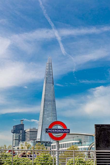 The London Underground sign at Tower Hill tube station, on a bright sunny day with the Shard in the background.