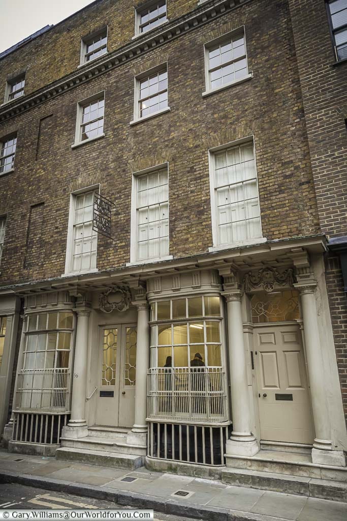 An elegant entrance to Georgian building in Artillery Lane in Spitalfields. The doors are flanked with columns, and the windows feature curved bay windows.