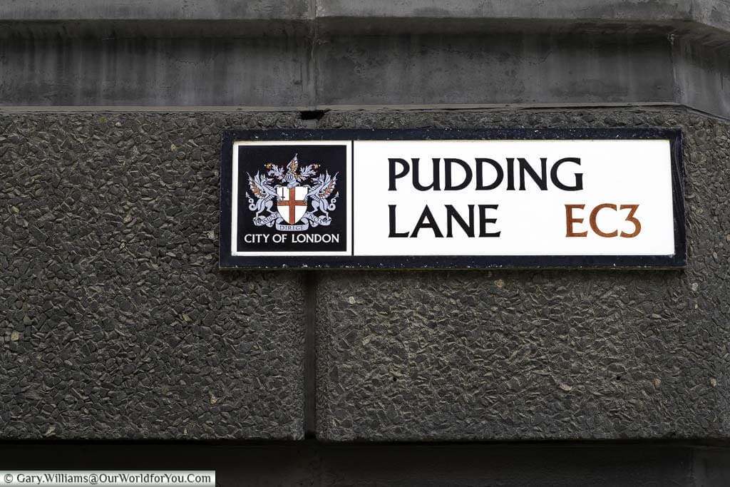 The street sign for Pudding Lane, attached to dark stonework, in the City of London