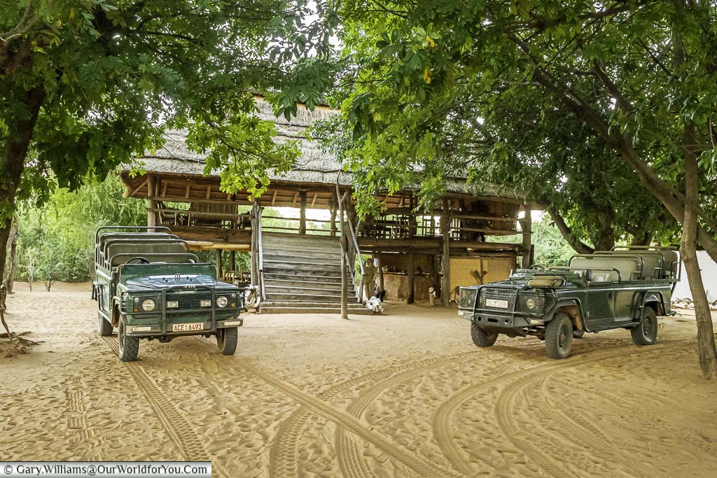 The two open topped safari Land Rovers parked in front of the Boma, or central gathering point, at the Rhino Safari Camp on Lake Kariba.
