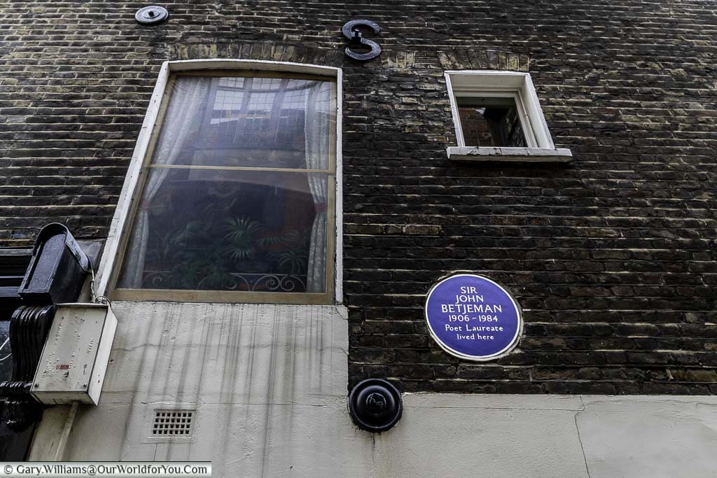 A blue plaque on the wall of a building to sir John Betjeman poet laureate.