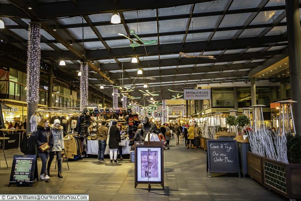 Looking into the bustling Spitalfields arts market that occupies an area where a market has been held for over 350 years. The stalls are covered by glass roof these days things have become a little more artisan.
