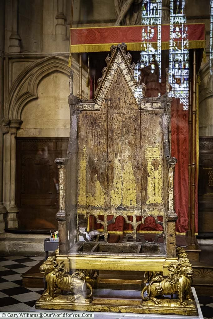 The ancient 13th-century english coronation chair behind a glass screen in westminster abbey in london