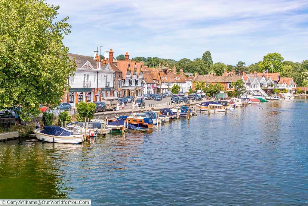 A number of small boats moored up at the Thames Riverside in Henley-on-Thames on a bright summers day.