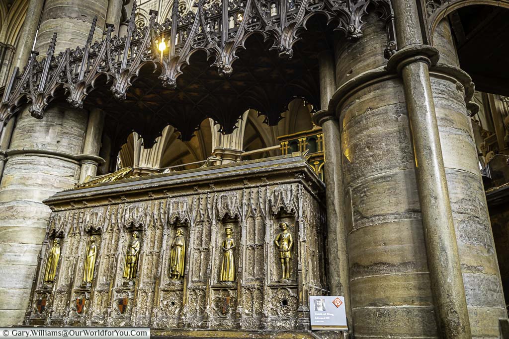The ornate tomb of King Edward III, embelished with gold figures, set between two pillars in westminster abbey in london
