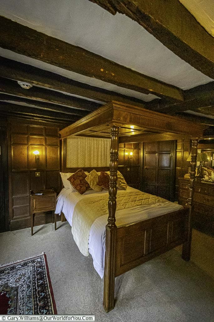 A small four-poster bed in a dark wood-panelled bedroom at the Mermaid Inn in rye, east sussex