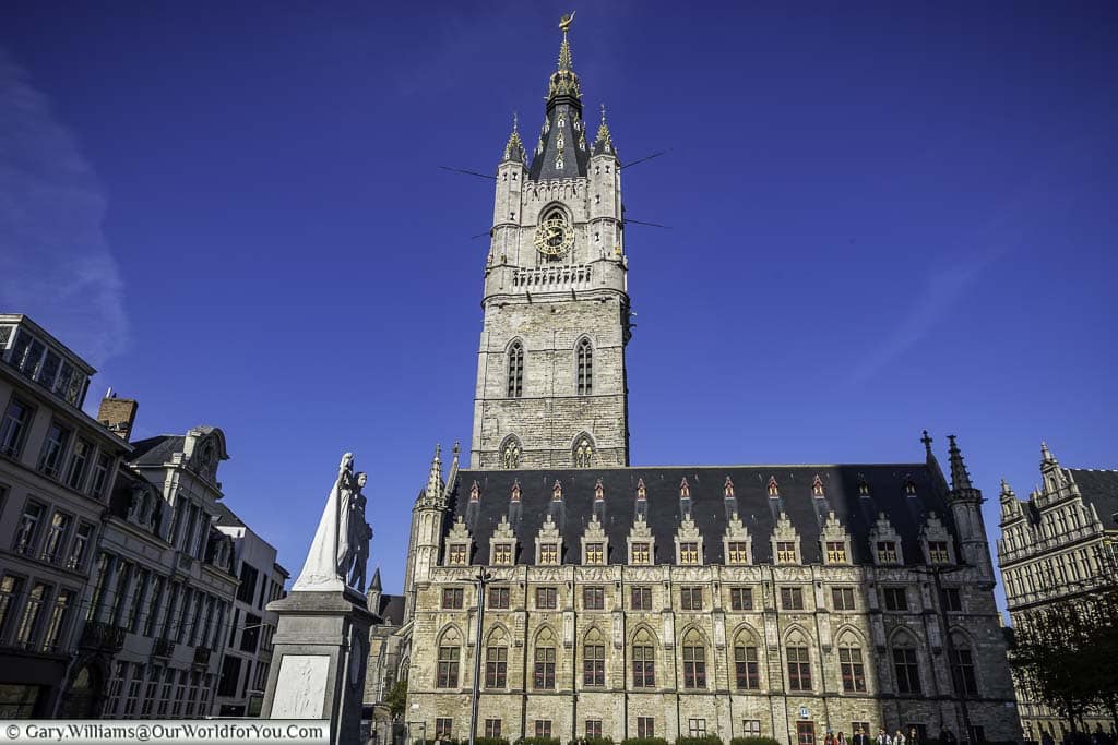 The view of ghent's histroic cloth hall with the city's belfry in the background set against a deep blue sky