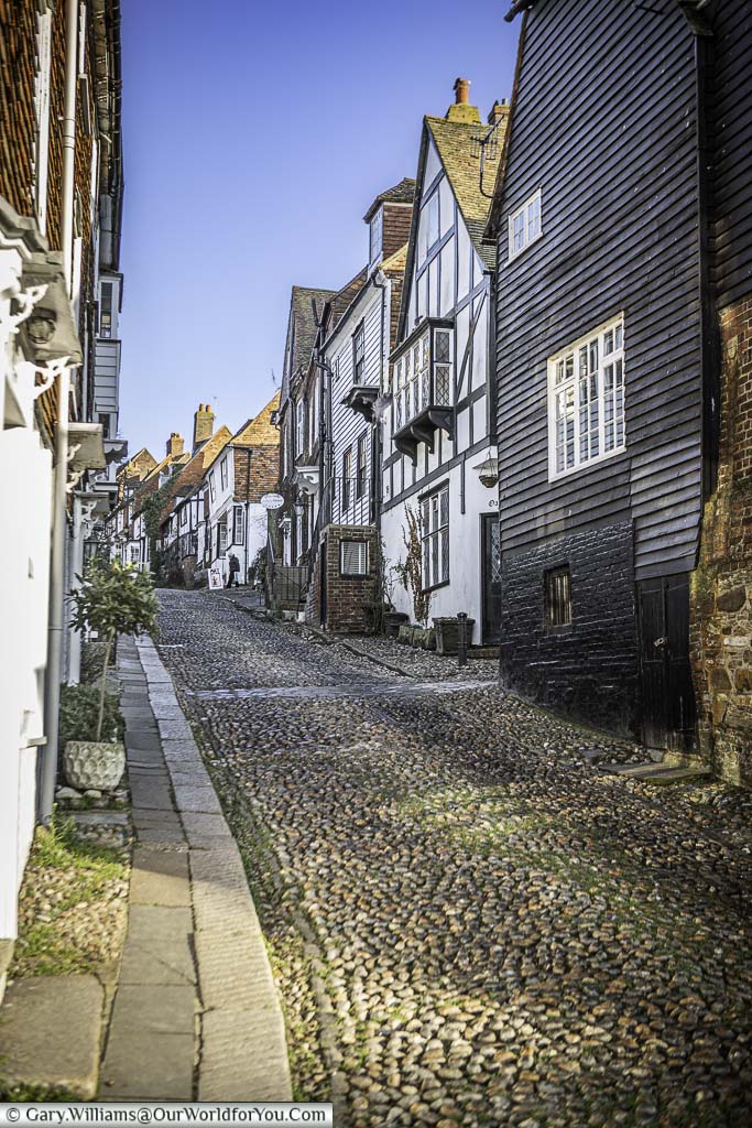 Looking up the cobbled mermaid street, lined with historic buildings, from the strand in rye, east sussex