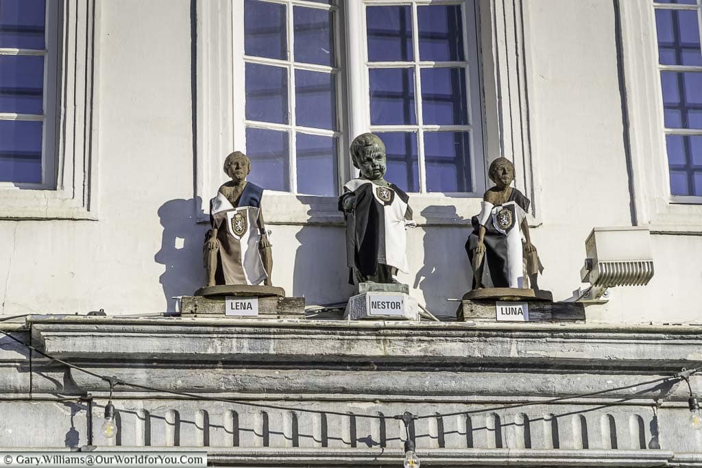 Three little statues above a doorway of a naughty boy and his two sisters, better know as a Manneke and Meisje Pis in Ghent, belgium