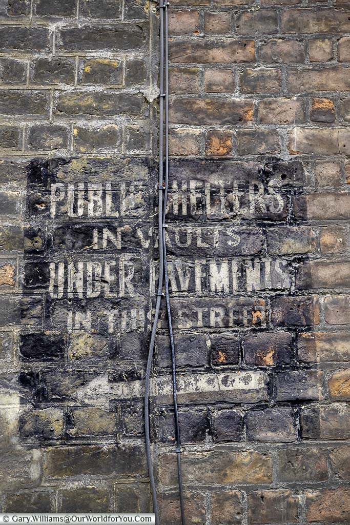 The stencilled sign on brickwork indicating the prence of an underground public air raid shelter in Westminster.