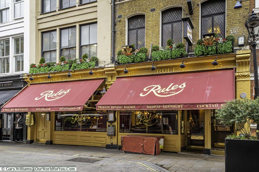 Red awnings above the windows of london's historic Rules restaurant in london's covent garden district