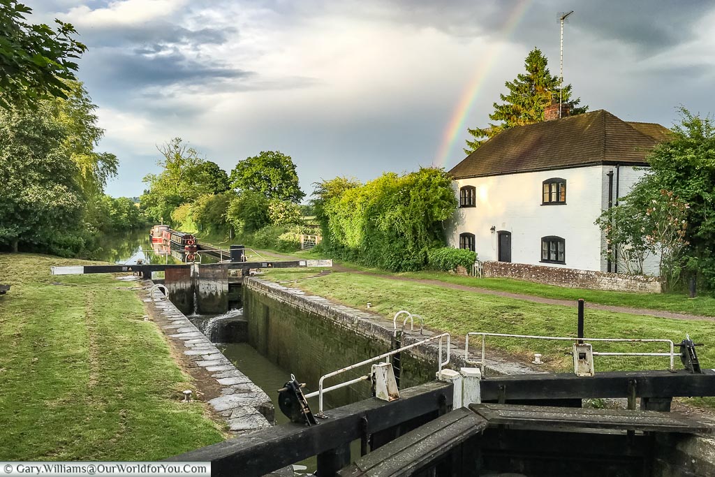 The old Lock Keepers house with a rainbow over it. In the distance is our wide beam canal boat just past the locks in the foreground.