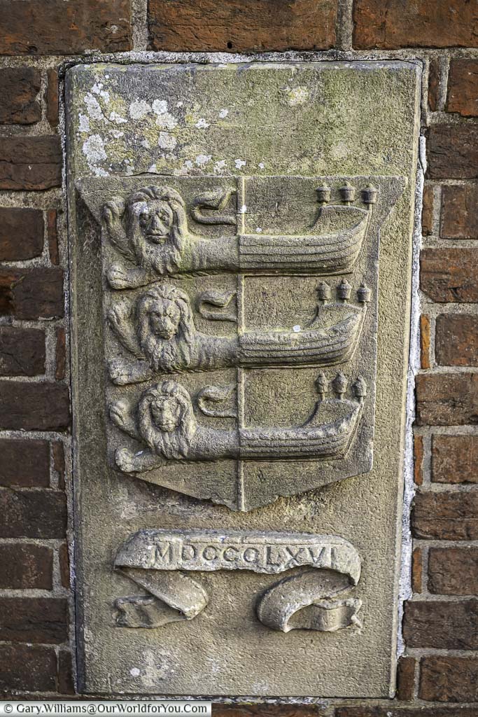 A stone tablet from 1866 set in a brick wall displaying rye's cinque port sign identifying this as one of east sussex's most historic towns