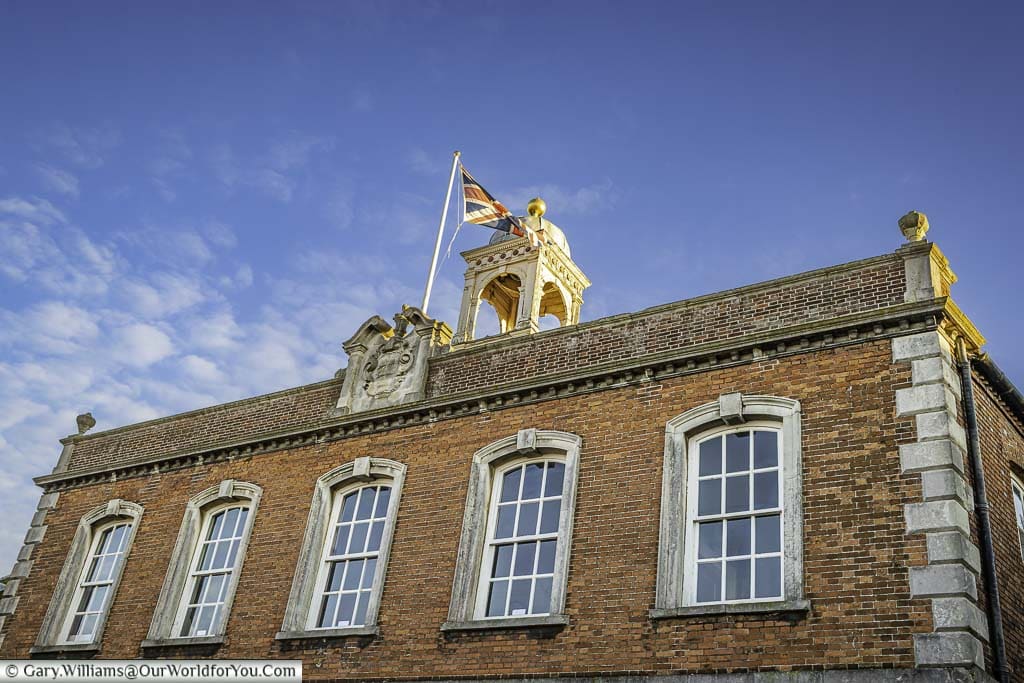 The top storey and roofline of the 18th-century townhall in rye with the union flag fluttering in the breeze